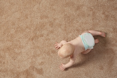 Photo of Cute little baby crawling on carpet indoors, top view with space for text