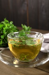 Photo of Aromatic herbal tea with parsley on wooden table, closeup