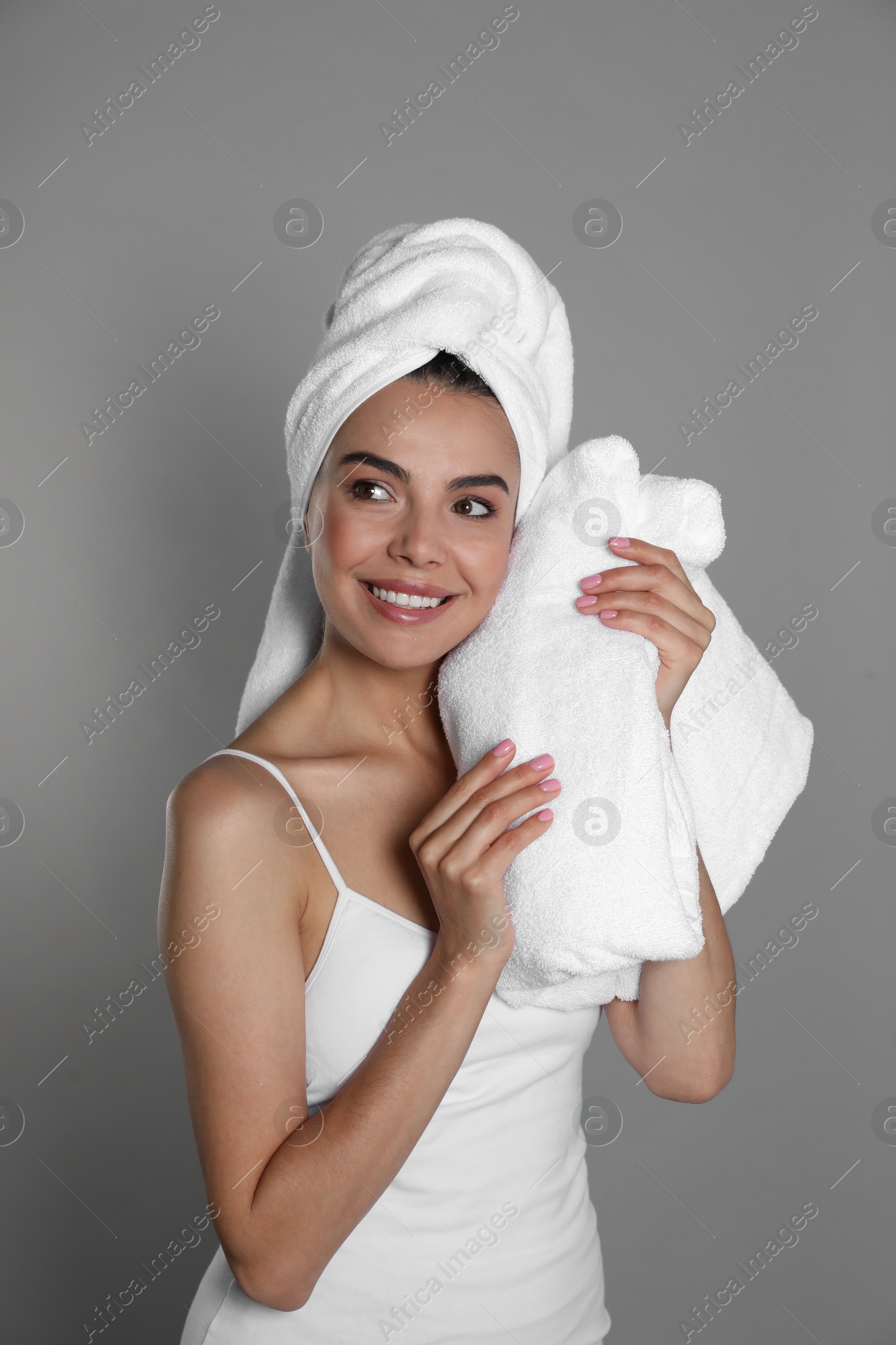 Photo of Beautiful young woman with towels on grey background