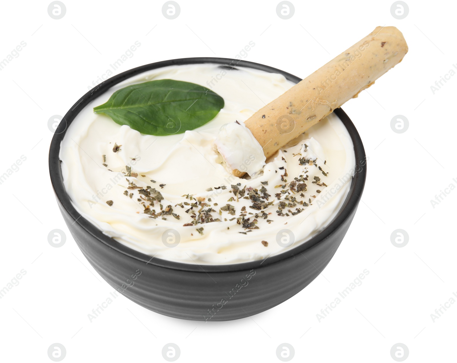 Photo of Bowl of delicious cream cheese with grissini stick, basil leaf and spices isolated on white