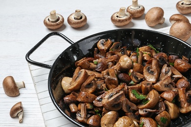 Photo of Frying pan with mushrooms on table, closeup