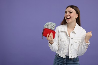 Photo of Excited woman holding wallet with dollar banknotes on purple background, space for text