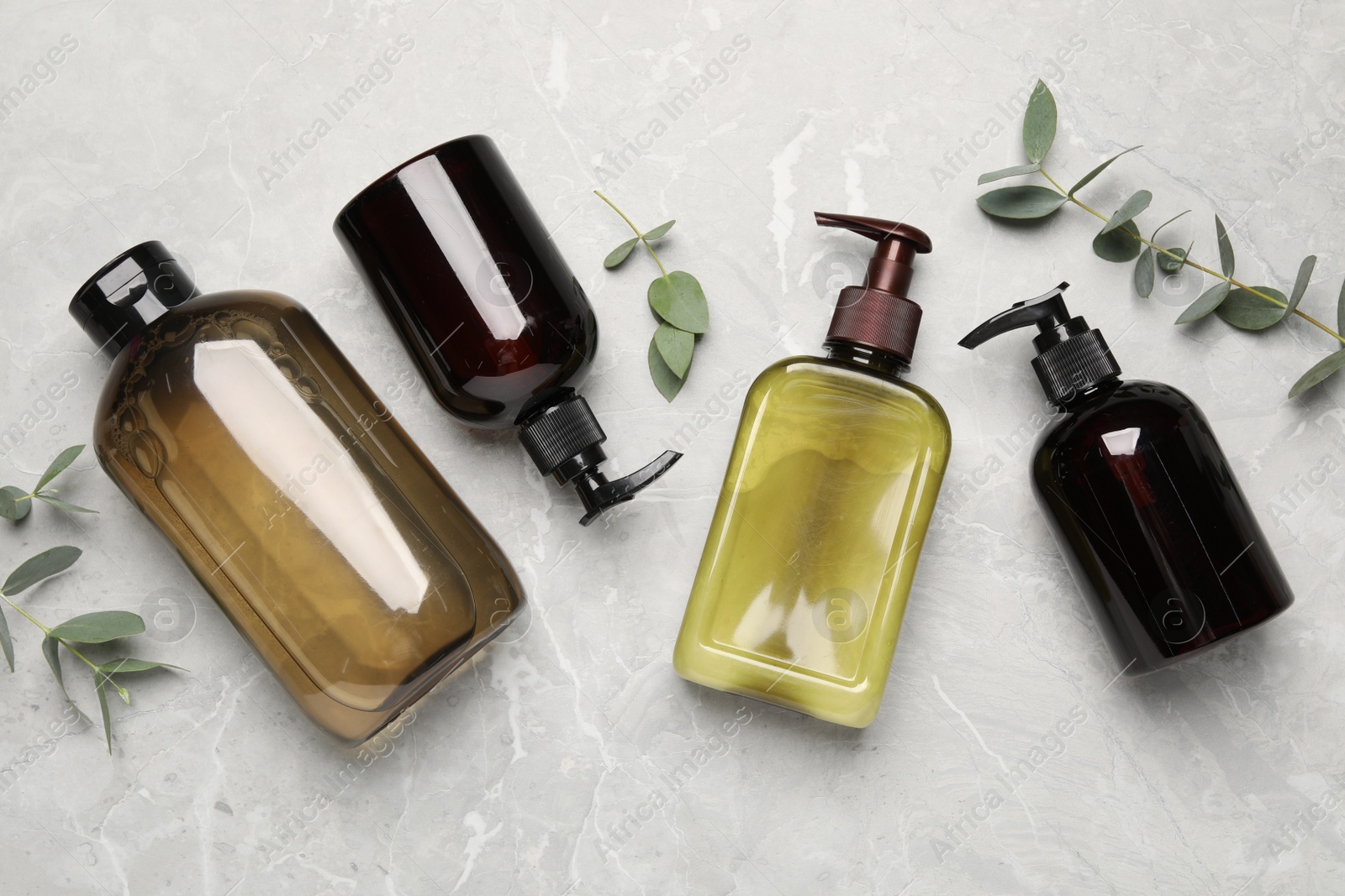 Photo of Shampoo bottles and leaves on white textured table, flat lay