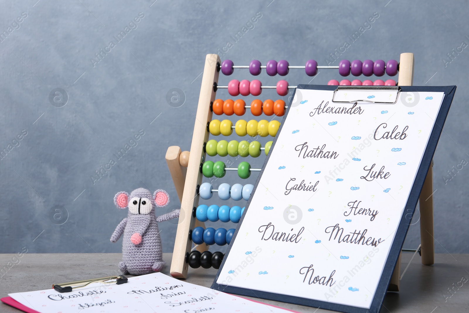 Photo of Clipboards with different baby names and toys on grey table