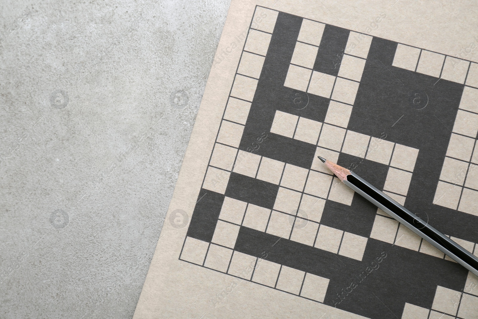 Photo of Blank crossword and pencil on old white table, top view. Space for text