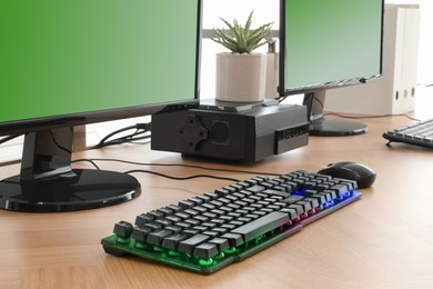 Photo of Modern computer and RGB keyboard on wooden table indoors