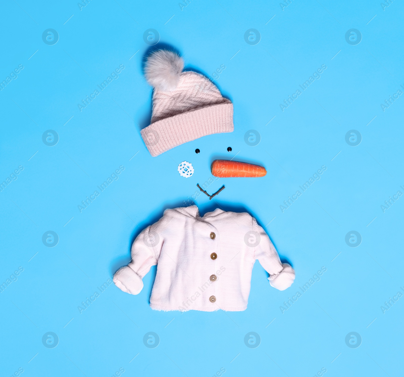 Photo of Creative snowman shape made of different items on light blue background, flat lay