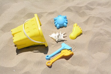 Photo of Bright plastic bucket and rakes on sand. Beach toys