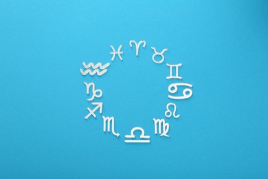 Photo of Zodiac signs on light blue background, flat lay