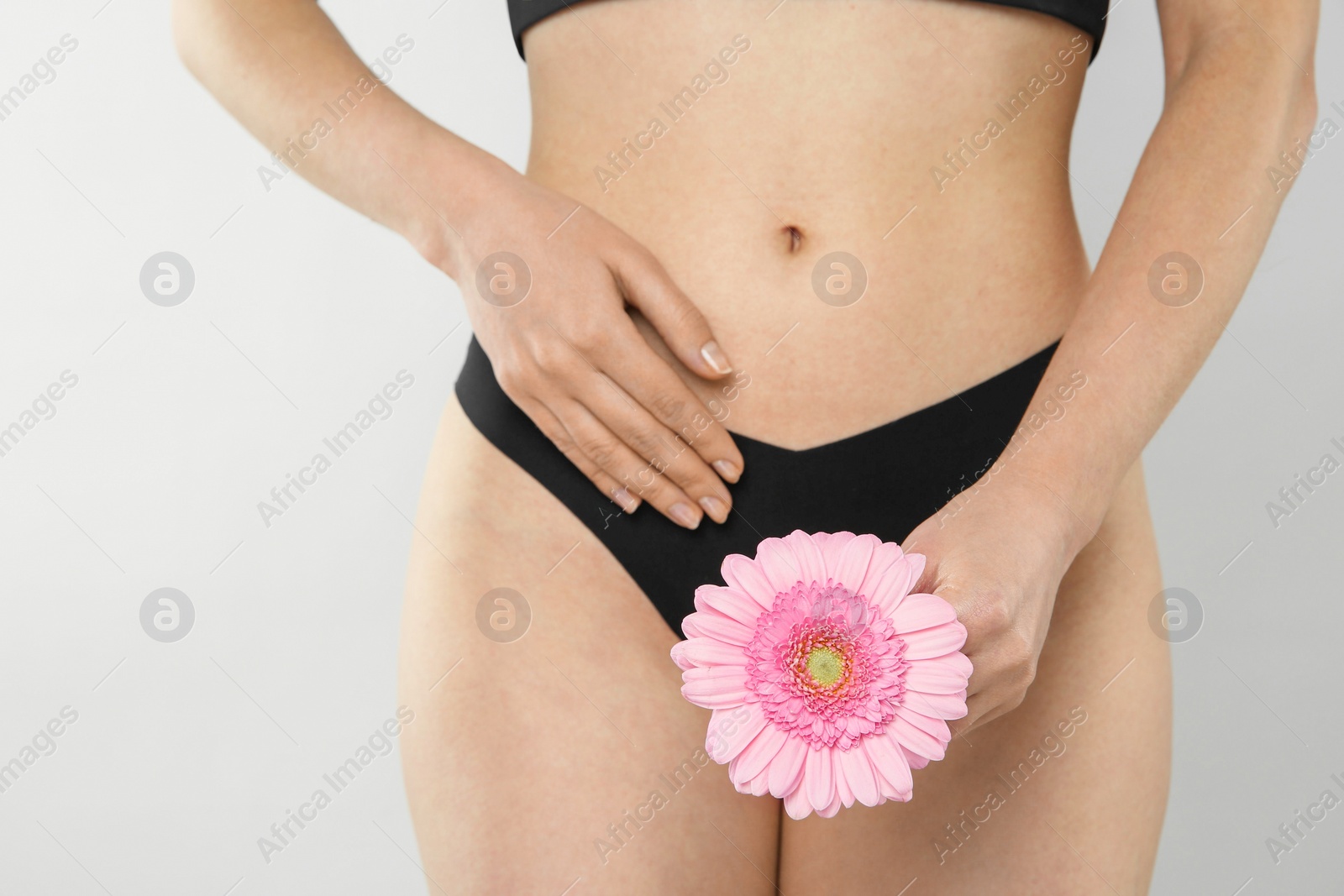 Photo of Gynecology. Woman in underwear with gerbera flower on light background, closeup