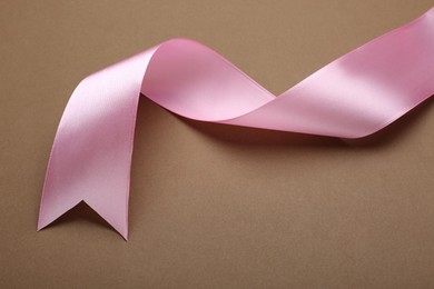 Photo of Beautiful pink ribbon on brown background, closeup. Space for text