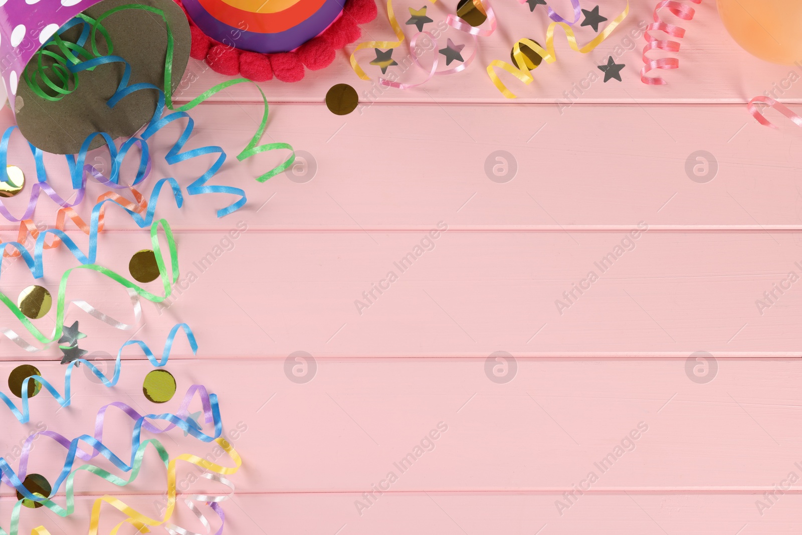 Photo of Flat lay composition with colorful serpentine streamers and confetti on pink wooden table, space for text