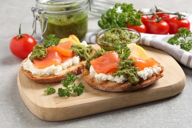 Photo of Delicious bruschettas with salmon, cream cheese and pesto sauce on light grey table