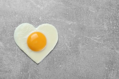 Photo of Heart shaped fried egg on light grey table, top view