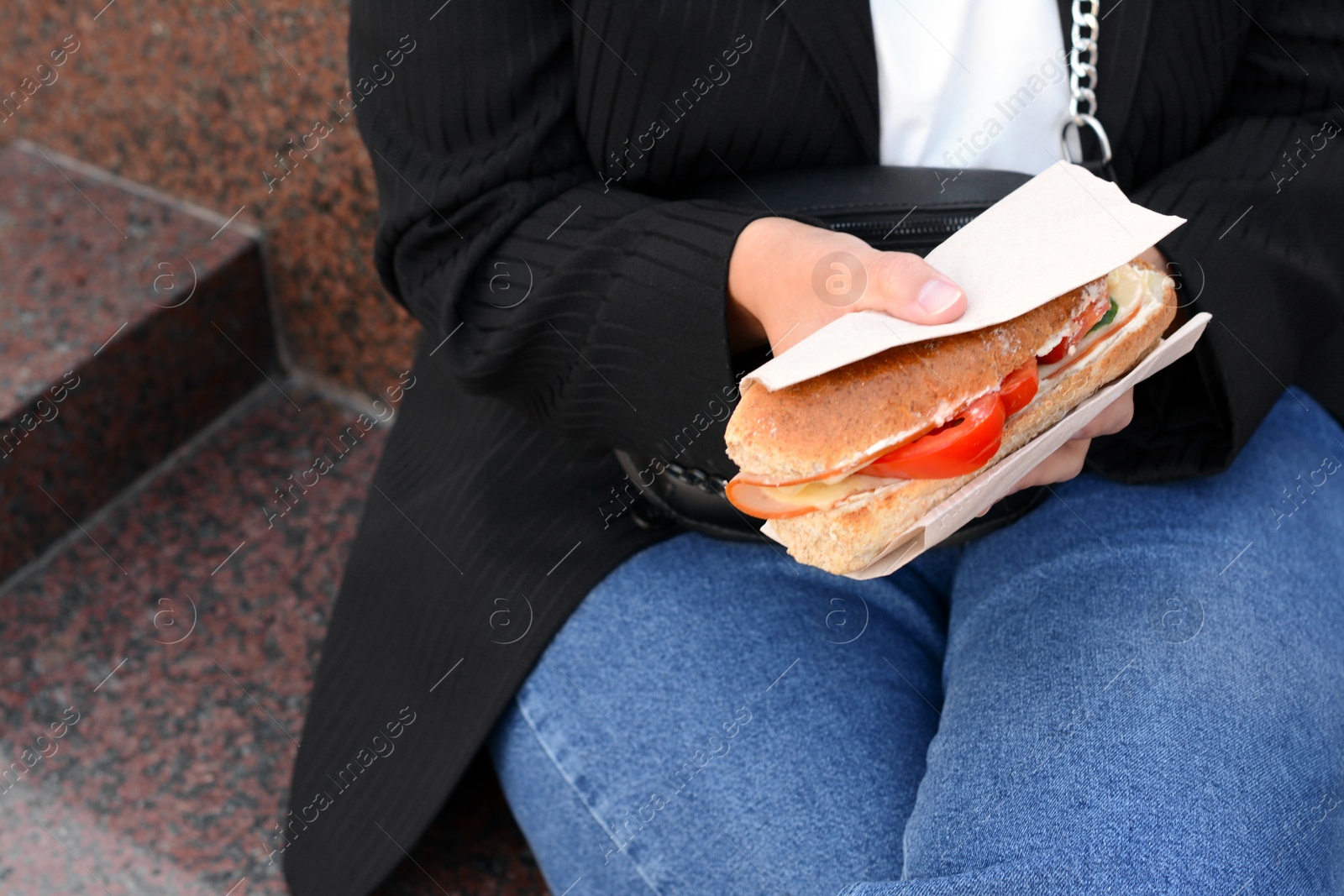 Photo of Woman holding tasty sandwich with vegetables outdoors, closeup. Street food