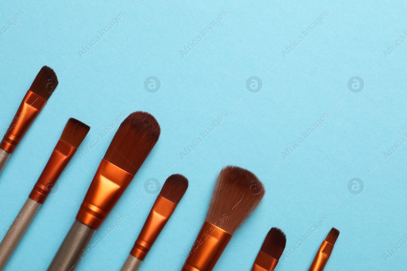 Photo of Set of makeup brushes on light blue background, flat lay. Space for text