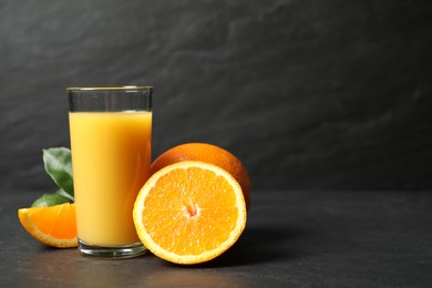 Photo of Glass of orange juice and fresh fruits on grey table. Space for text