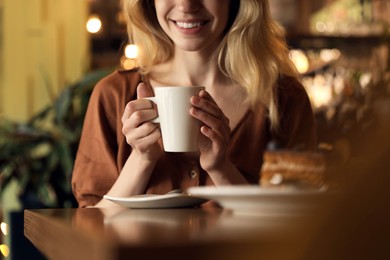 Photo of Young woman with cup of coffee at cafe in morning, closeup