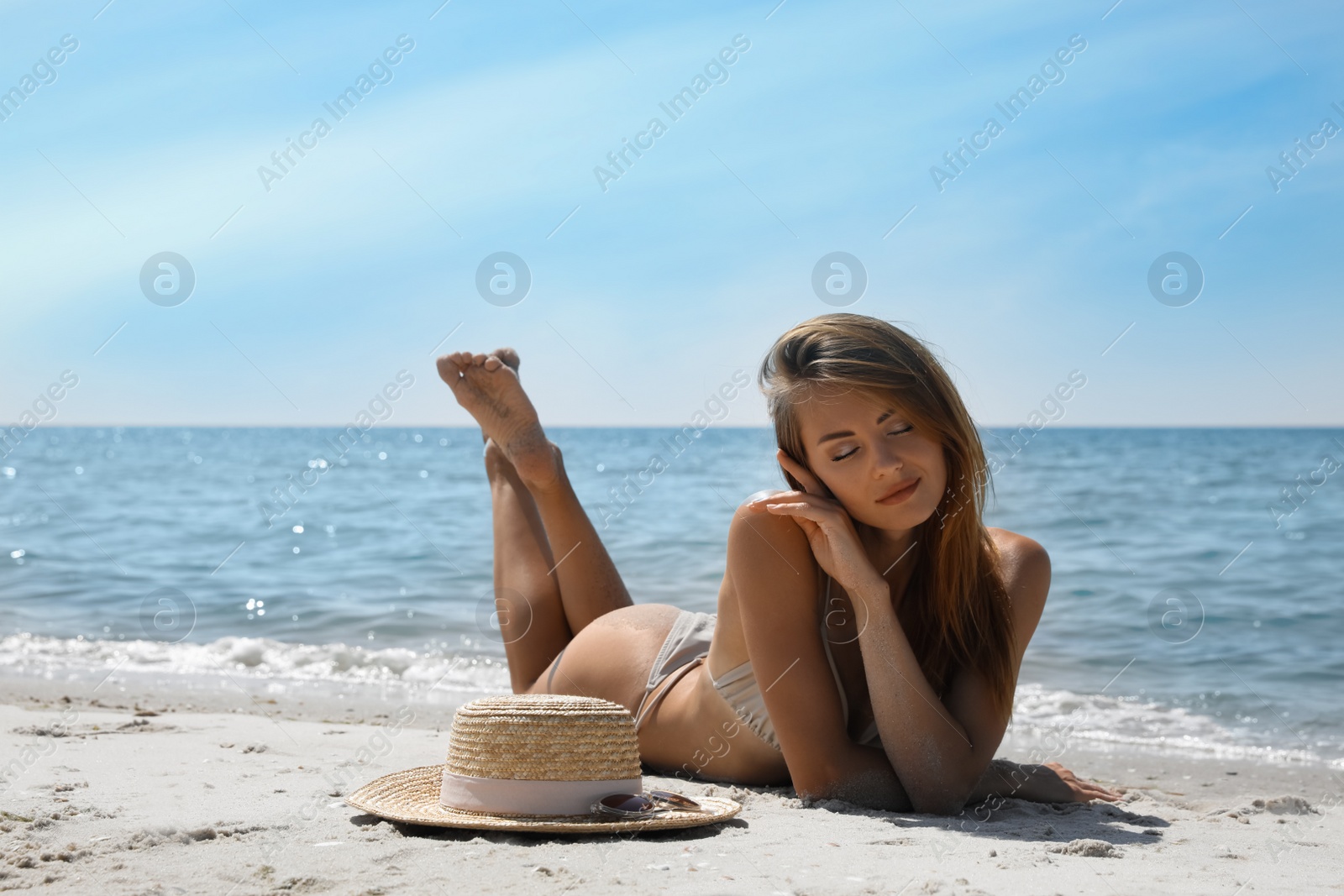 Photo of Attractive woman in bikini lying on sandy beach near sea