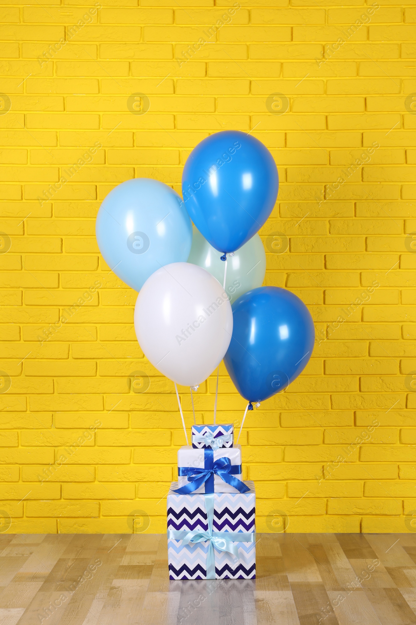 Photo of Gift boxes and balloons near yellow brick wall