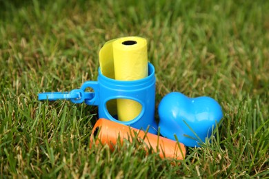 Rolls of colorful dog waste bags on green grass outdoors