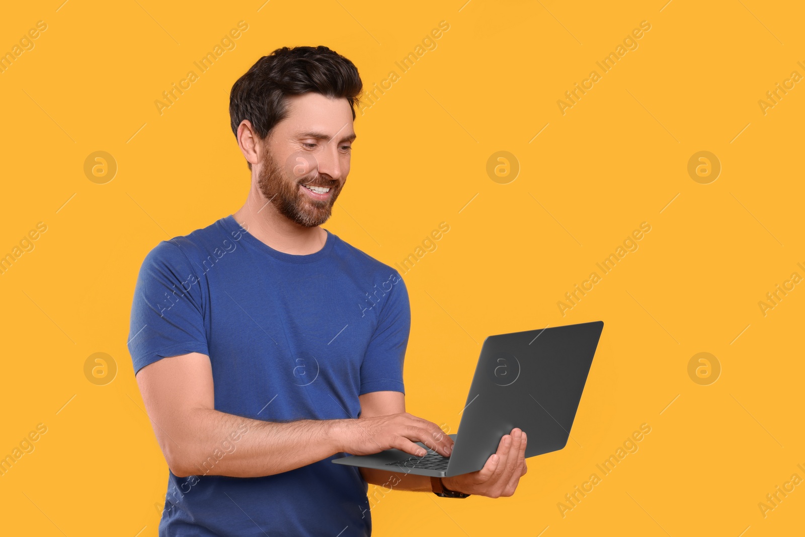 Photo of Happy man with laptop on yellow background