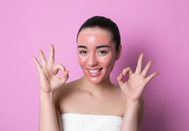 Woman with pomegranate face mask showing Ok on pink background