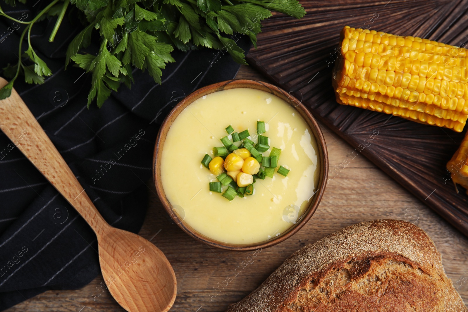 Photo of Delicious corn cream soup served on wooden table, flat lay