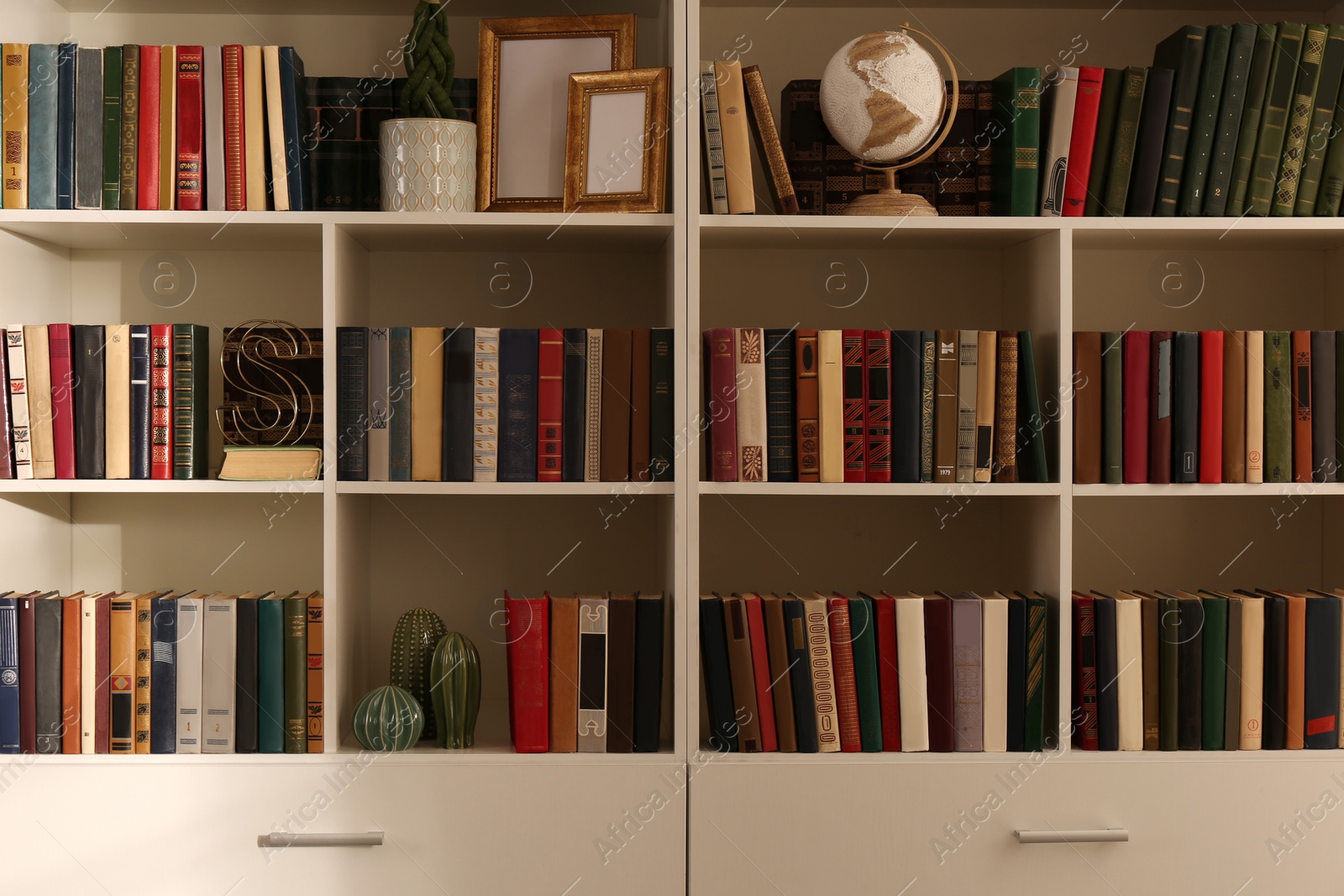 Photo of Collection of different books and decorative elements on shelves in home library