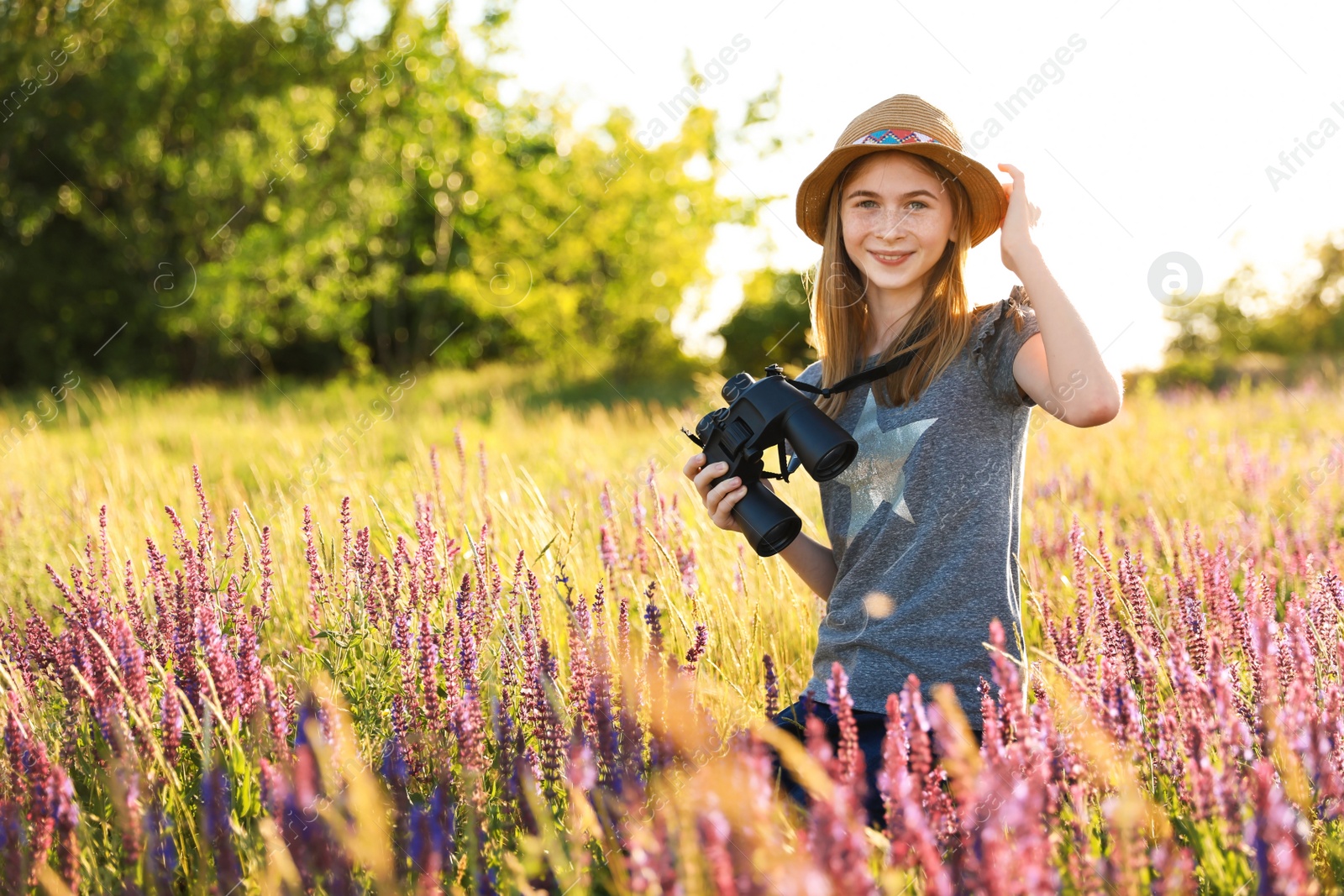 Photo of Teenage girl with binoculars in field. Summer camp