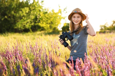 Teenage girl with binoculars in field. Summer camp
