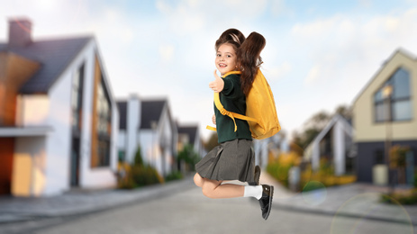 Image of Happy girl jumping on street. School holidays