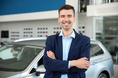 Portrait of young salesman in car dealership
