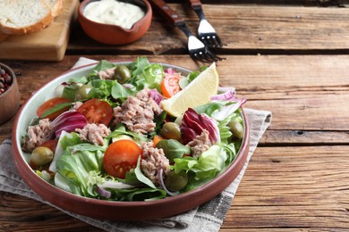 Photo of Plate of delicious salad with canned tuna and vegetables served on wooden table, space for text