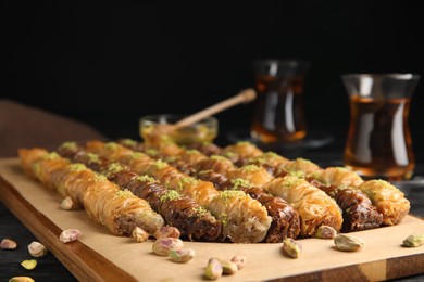 Photo of Delicious sweet baklava with pistachios on wooden board, closeup