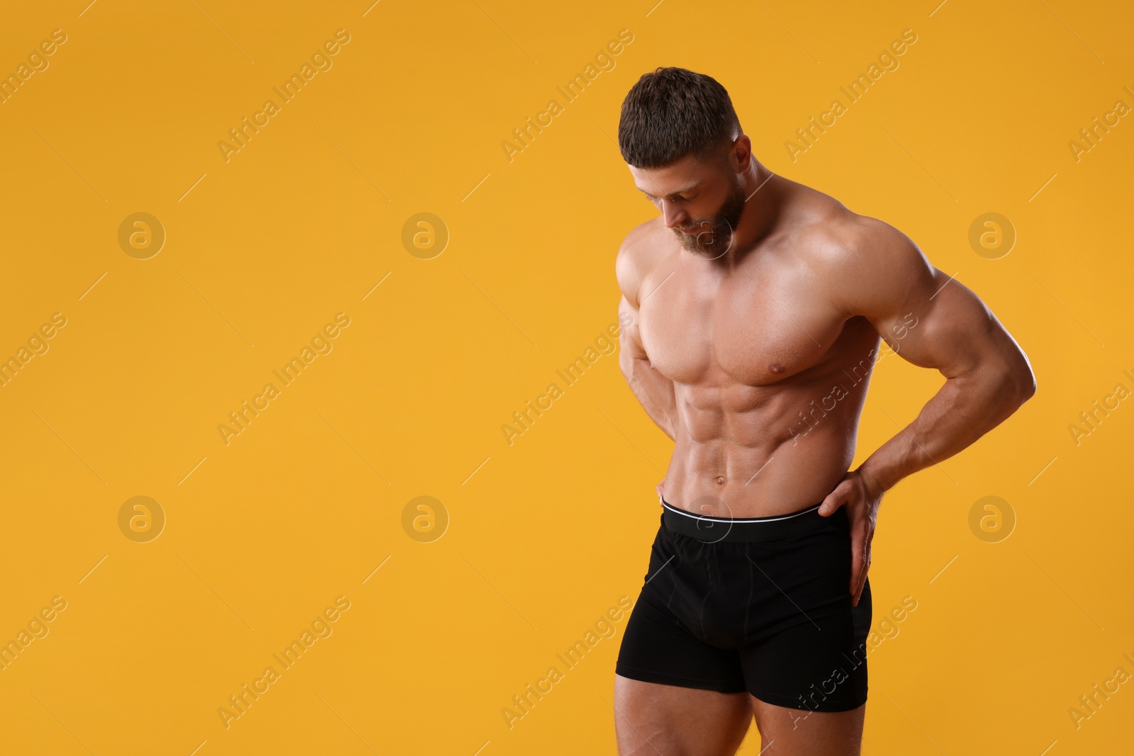 Photo of Young man is stylish black underwear on orange background