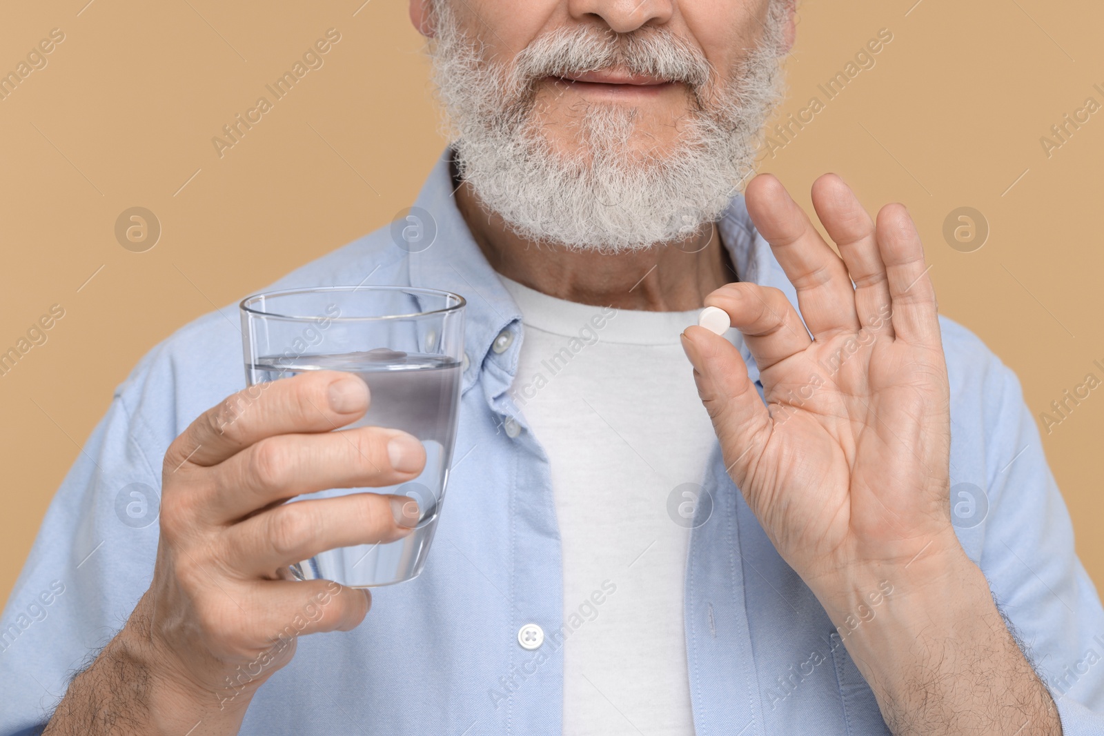 Photo of Senior man with glass of water and pill on beige background, closeup