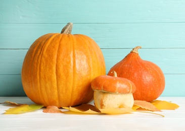 Photo of Different pumpkins on table against wooden wall. Autumn holidays