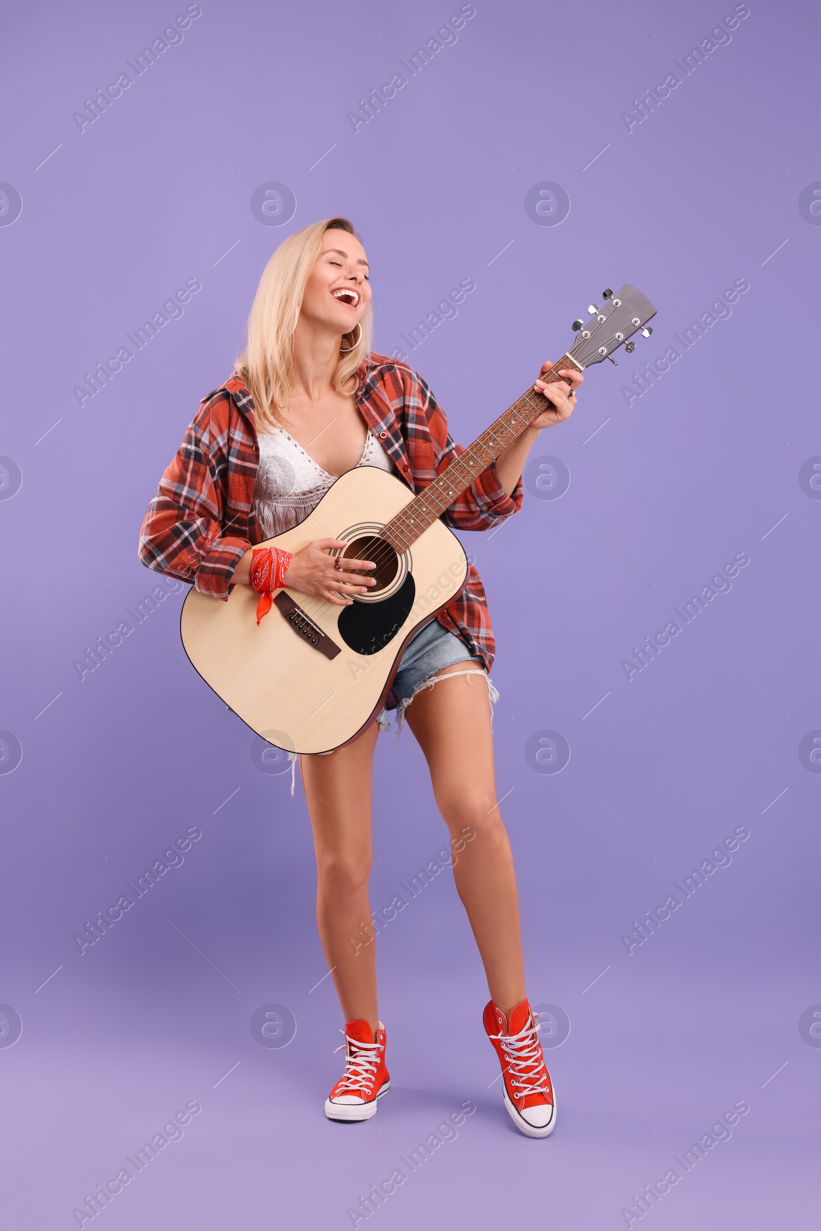 Photo of Happy hippie woman playing guitar on purple background