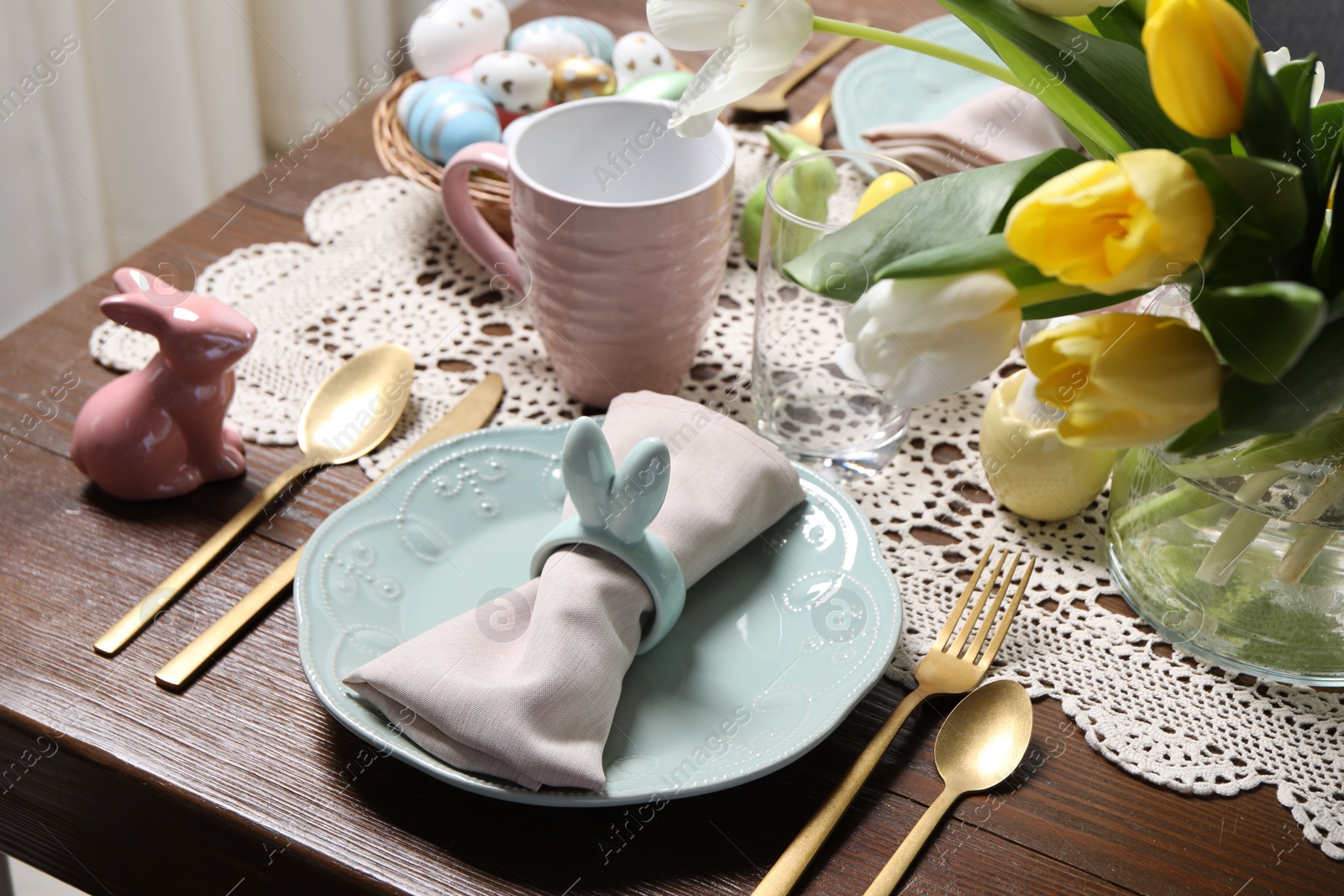 Photo of Festive table setting with napkin ring in shape of bunny ears, closeup. Easter celebration