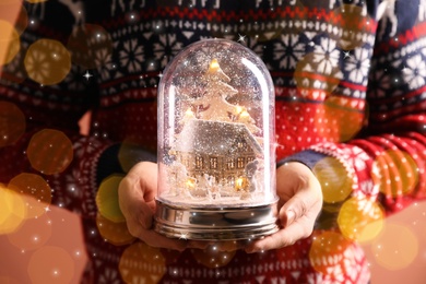 Image of Man holding snow globe on color background, closeup. Bokeh effect