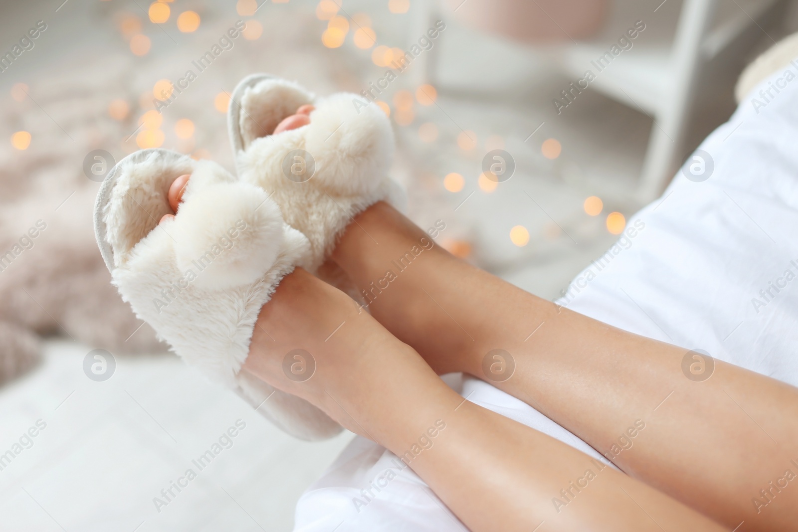Photo of Young woman with sexy legs in fluffy slippers indoors