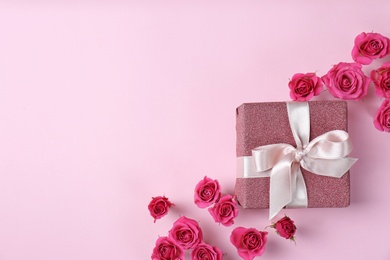 Photo of Beautiful roses and gift box on color background, top view. Space for text