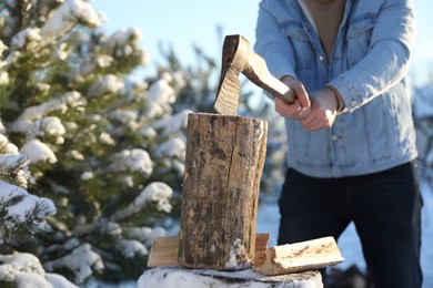 Man chopping wood with axe outdoors on winter day, closeup. Space for text