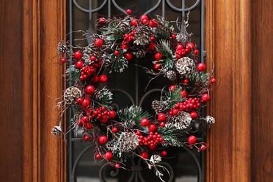 Photo of Beautiful Christmas wreath hanging on wooden door