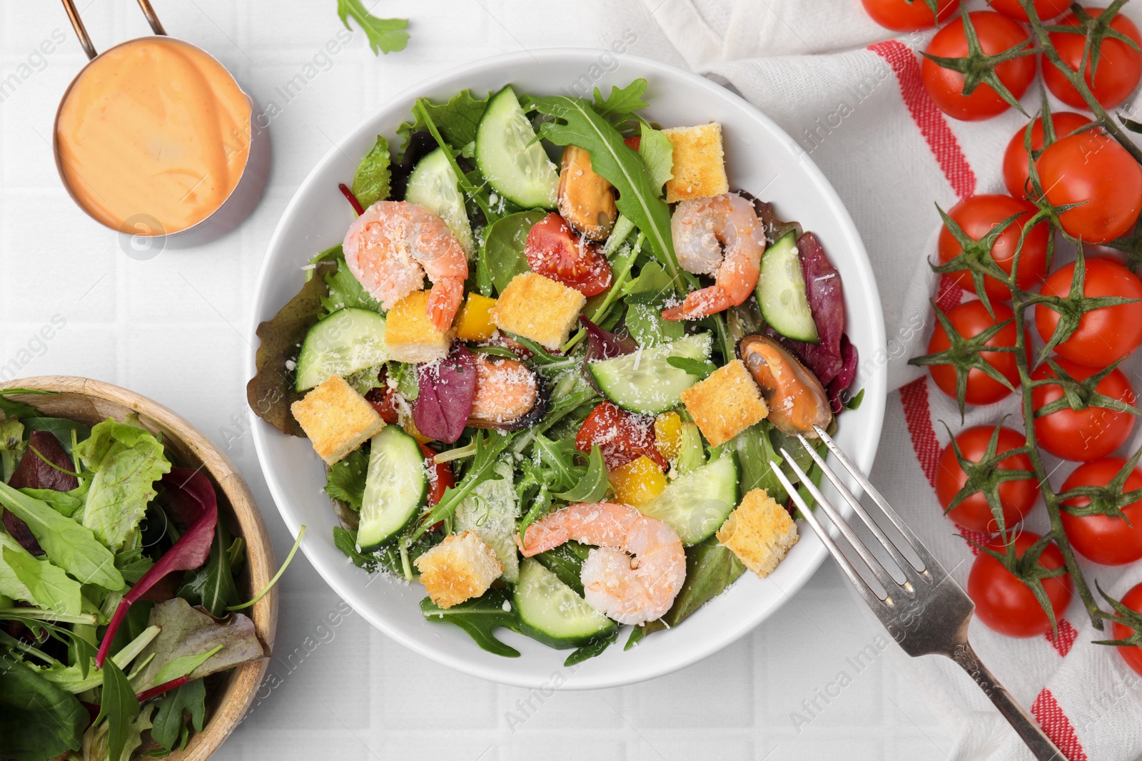 Photo of Delicious salad with croutons, cucumber and shrimp served on white tiled table, flat lay