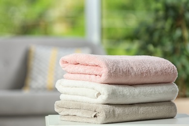 Stack of folded clean soft towels on table indoors. Space for text