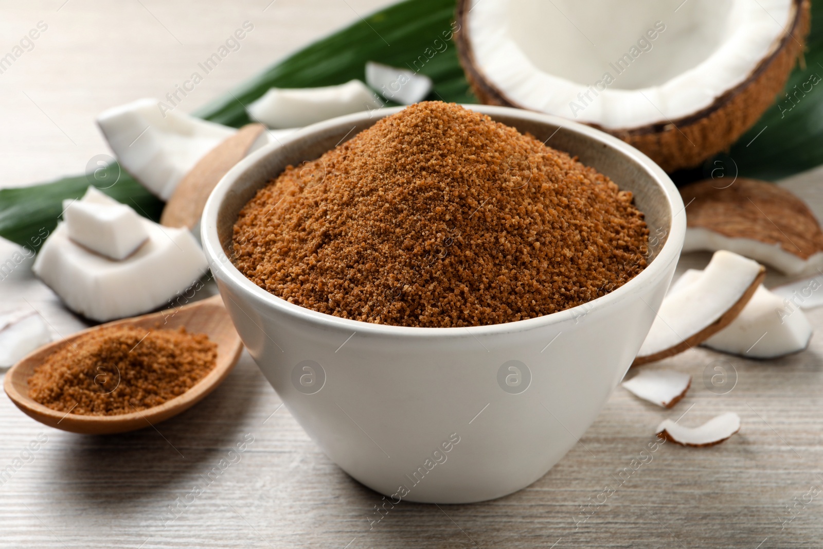 Photo of Natural coconut sugar in bowl on white wooden table