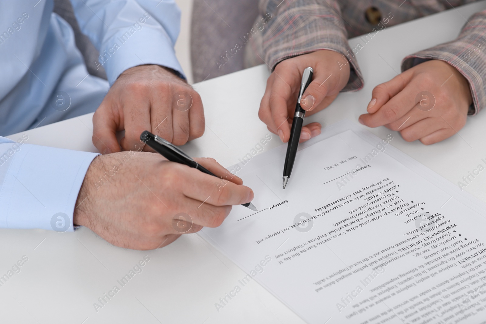 Photo of Businesspeople signing contract at white table, closeup of hands