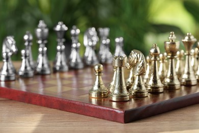 Photo of Chess board with pieces on wooden table against blurred background